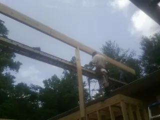 Carpenter setting a ridge beam over a new addition frame — Ice Dam Removal by Roofing Brothers in Ely
