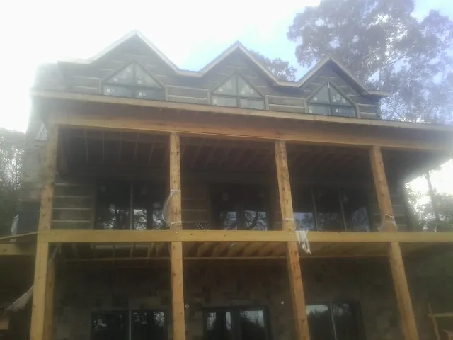 Dormers and porch framing on a large log home under construction — Roof Coating work by our crew in Ely