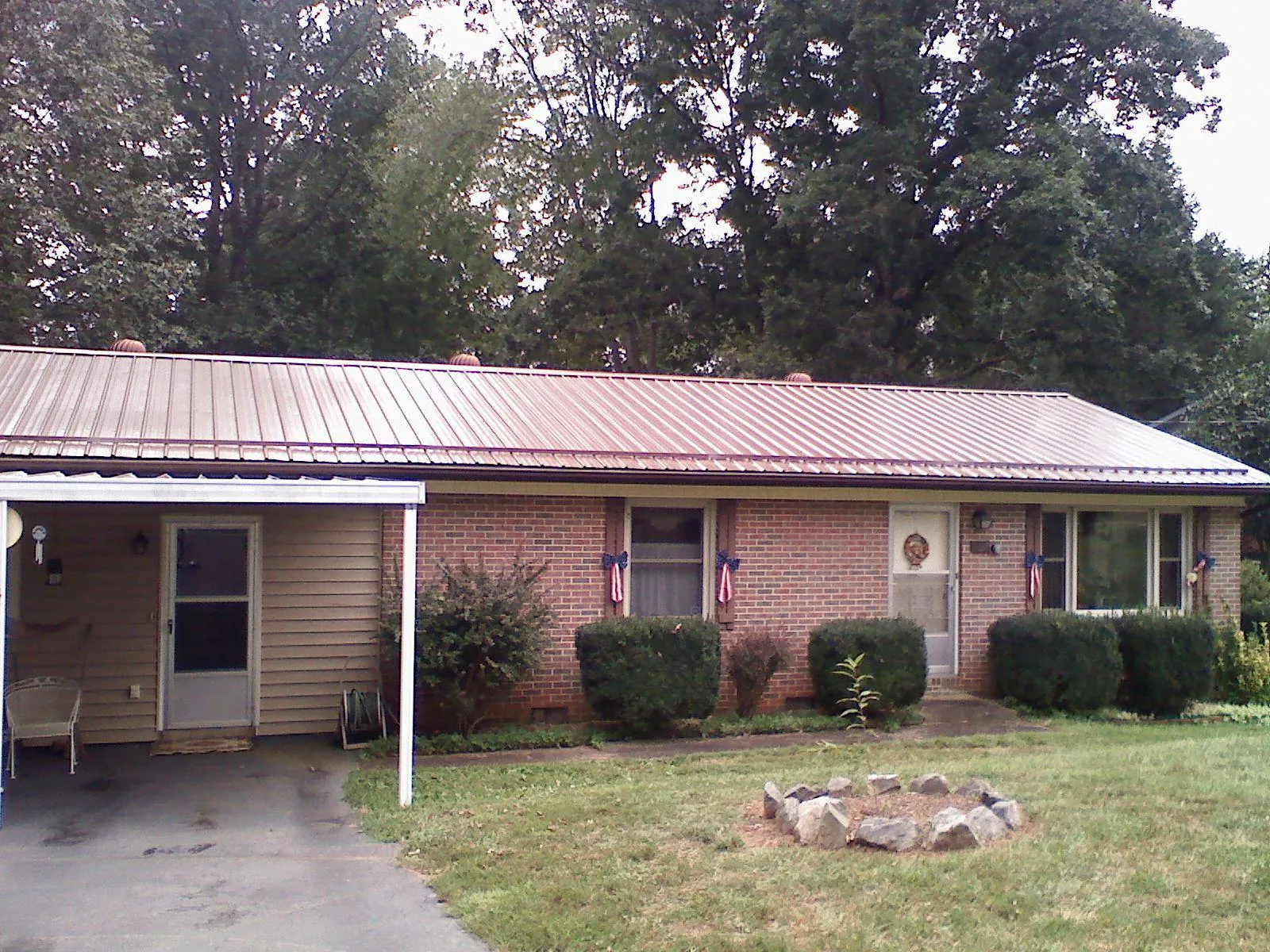 Bronze metal roof and carport on a brick ranch home — Roof Repair work by our crew in Ely