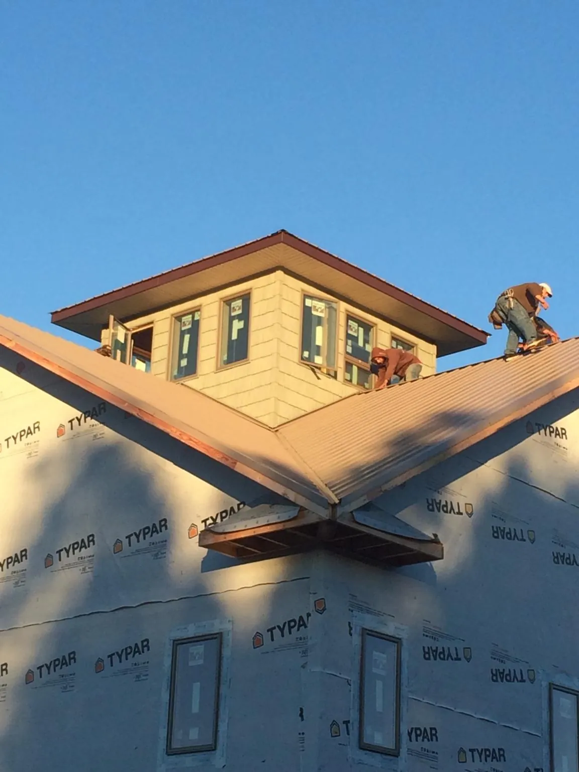 Roofers working around a rooftop cupola on a new metal roof at sunset — Roof Waterproofing in Ely by Roofing Brothers